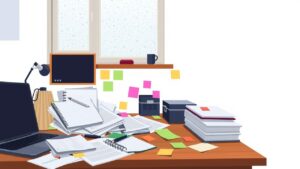 Een rommelig kantoorbureau met laptop, plakbriefjes en papieren planners.